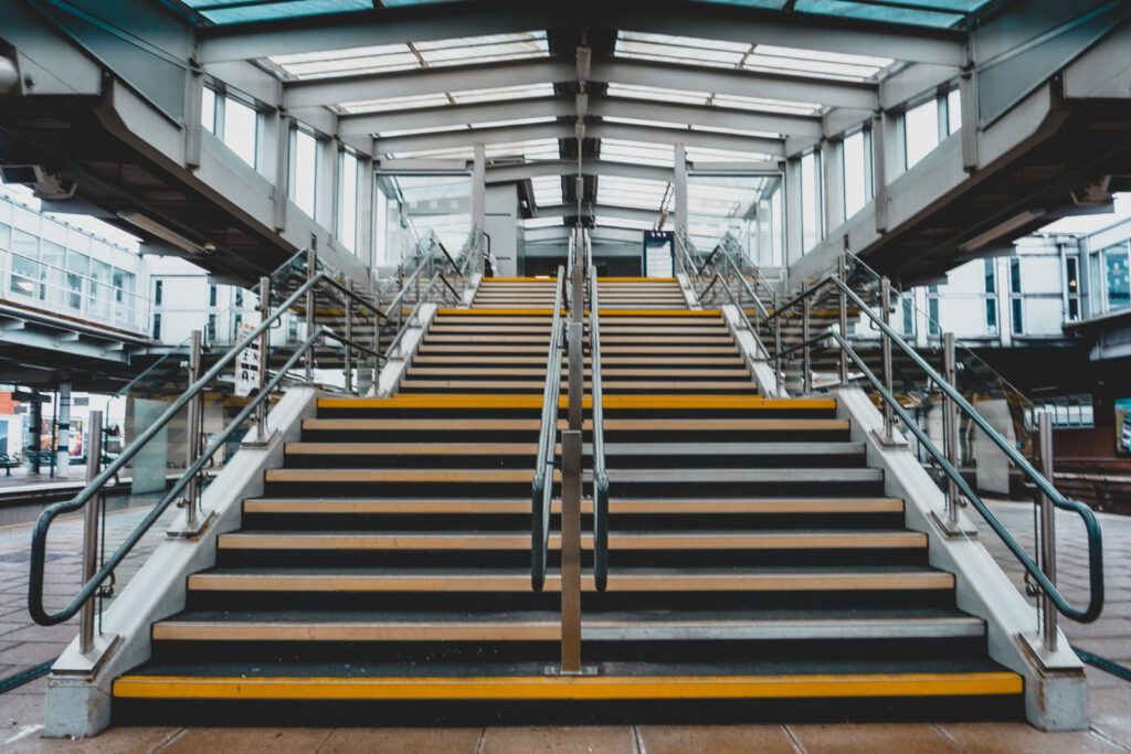 Innentreppe mit gelb markierten Stufenkanten und Stahlhandläufen – Industrietreppen rutschfest machen
